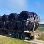 Water Services NZ truck delivering large coils of water piping for rural infrastructure installation.
